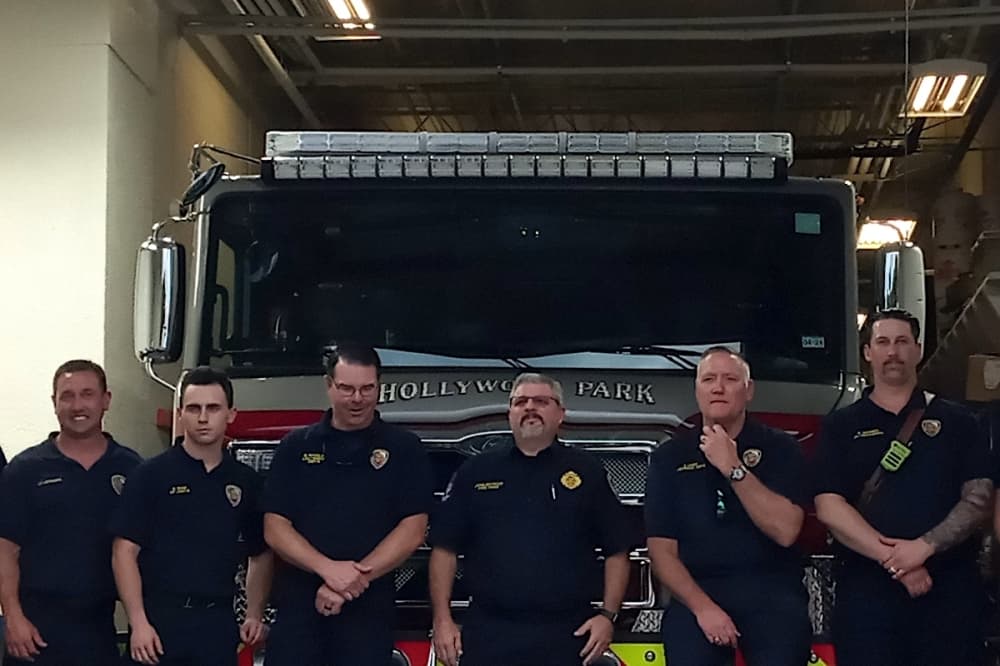 Hollywood Park Fire Department Chief John Butrico (third from right) stands with fellow firefighters in front of their new ladder truck at the entrance of the recently extended HPFD station bay. (Edmond Ortiz/Community Impact)