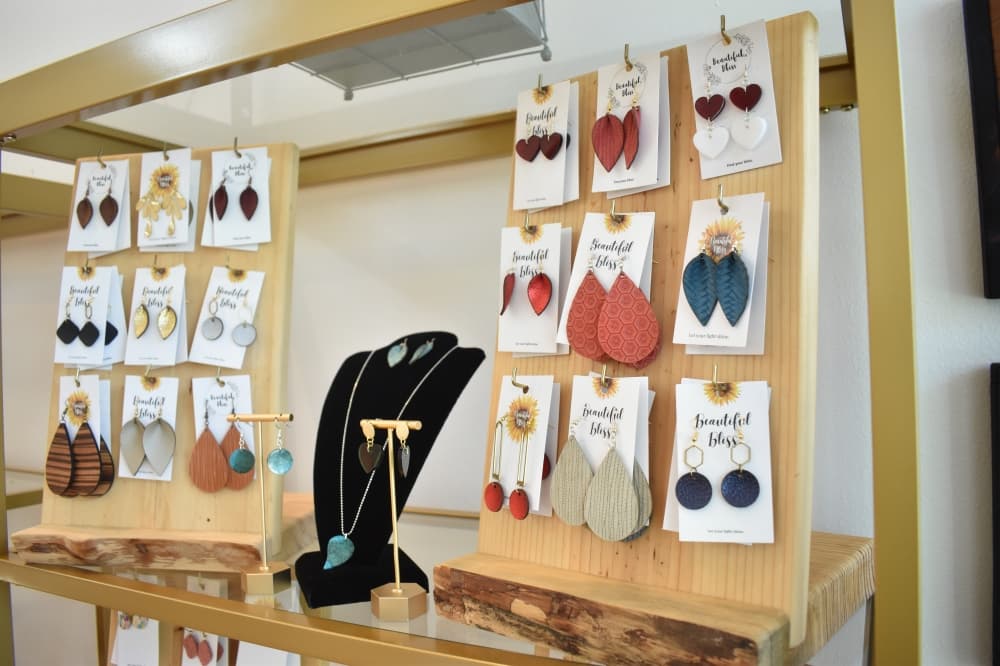 Two jewelry stands filled with earrings sit on a shelf, separated by a necklace stand.