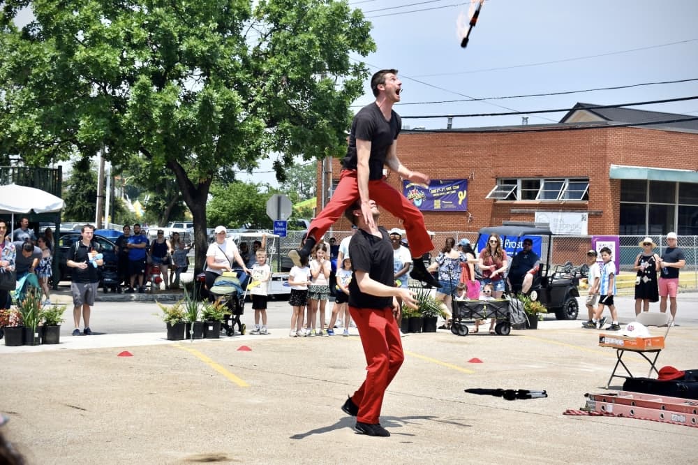 a man jumps over another while grabbing a flaming baton