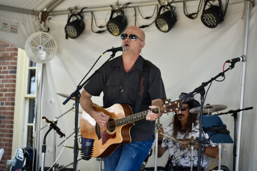 a man in a black shirt plays a guitar and sings on stage