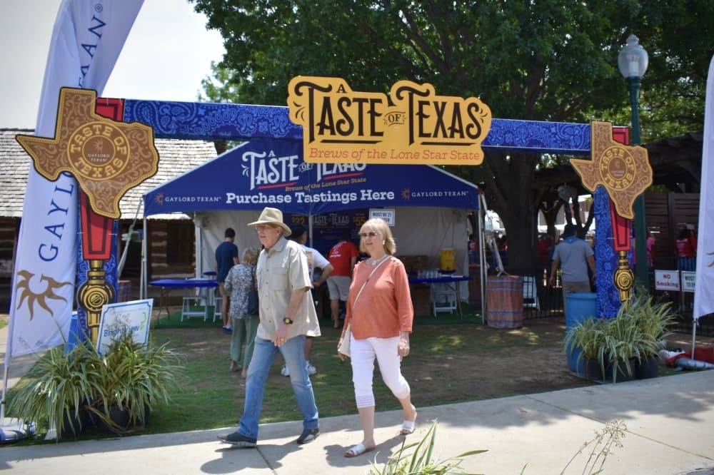 people walk past a large blue entranceway to a tasting event