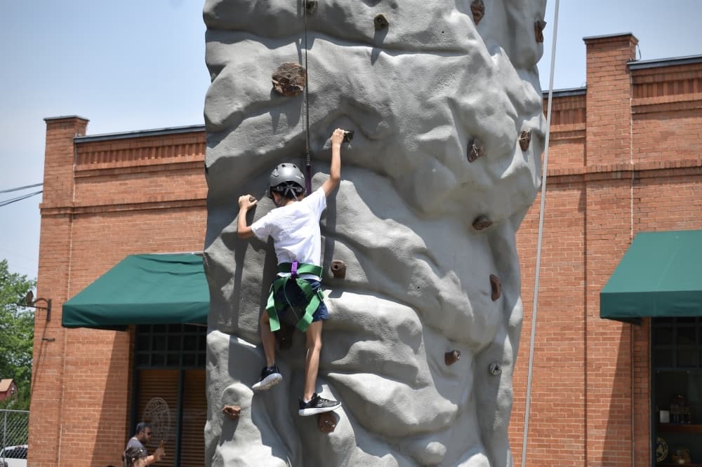 a young child goes up a rock climbing wall 