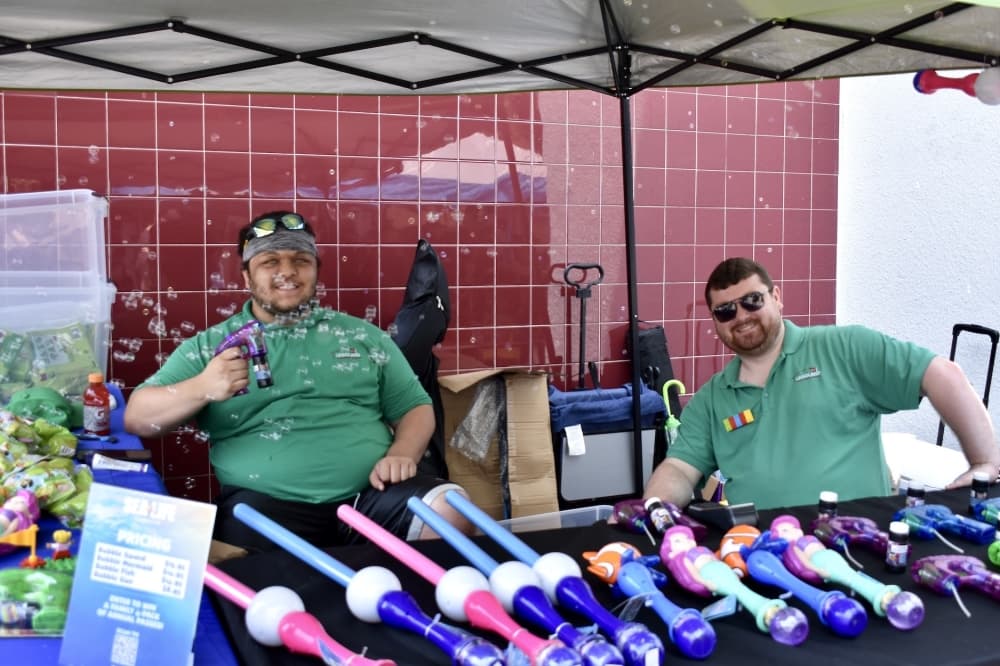 two men sit in a tent while selling bubble wands