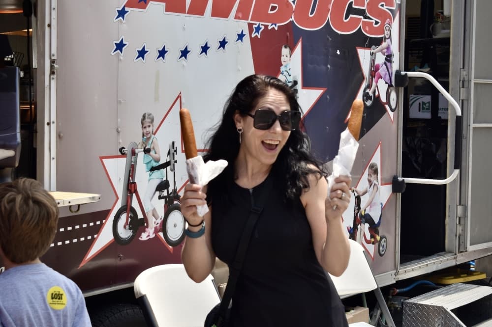 a woman poses while holding two corndogs
