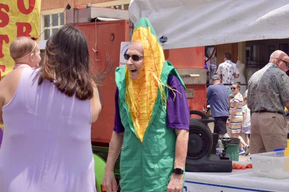 a man in a corn in the cob costumes smiles at a baby 