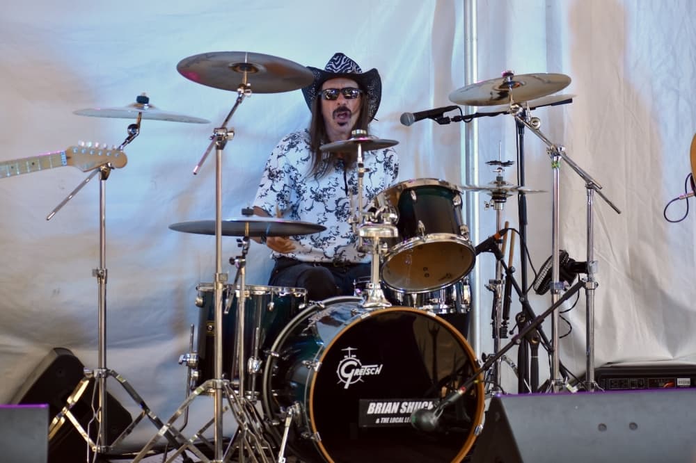 a man in a cowboy hat plays the drums