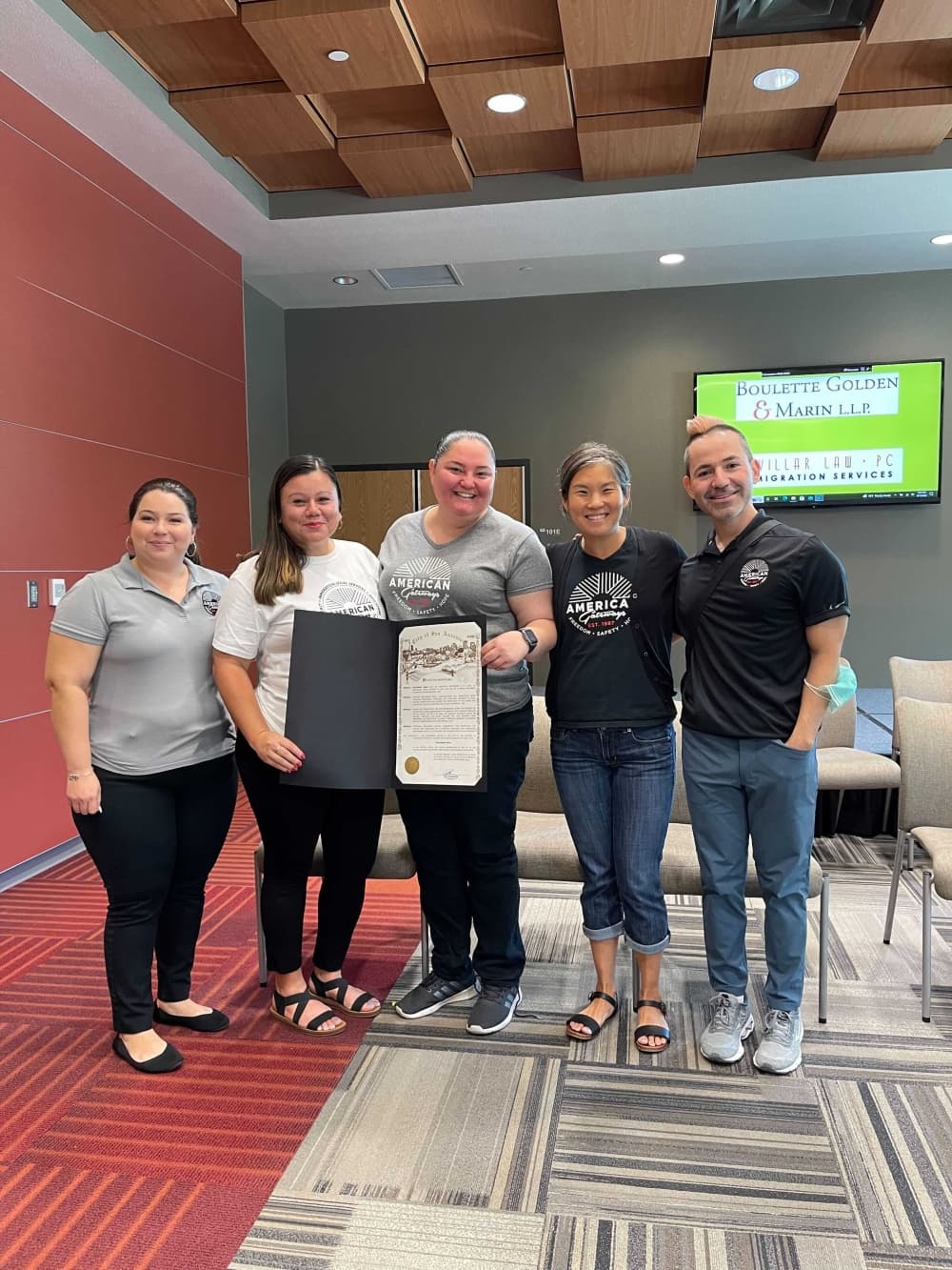 five employees lined up in a row holding a proclamation
