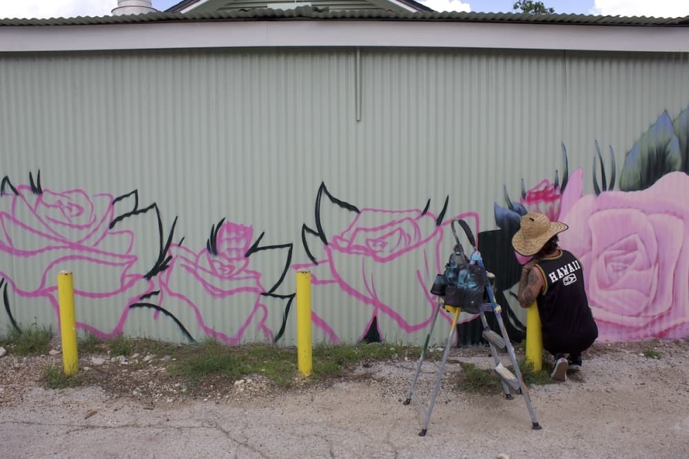 Muralist Austin Sepulveda paints the side of the Rose Haven building.