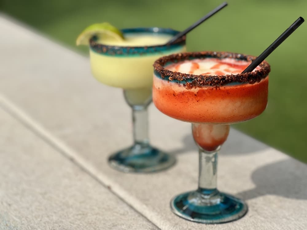 two drinks on a table with grass in the background 