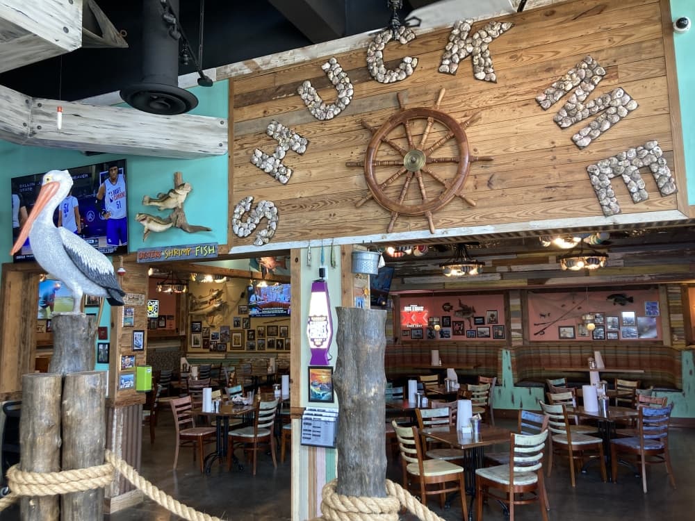 restaurant interior decorated with nautical decor and sign reading "shuck me" 