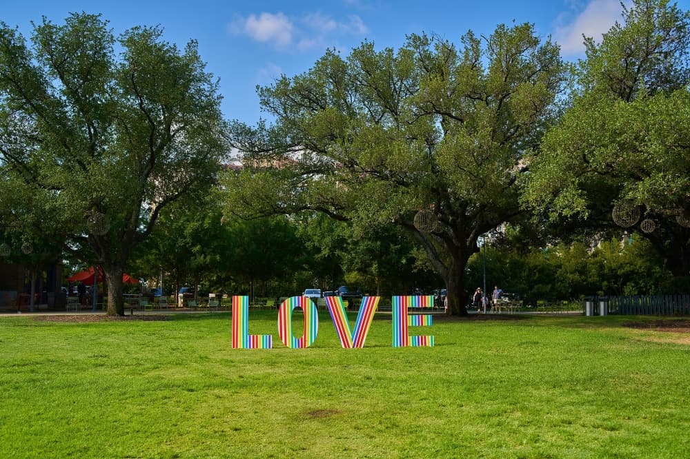 A rainbow-striped sign reads "LOVE" at the Pride with Families event at Levy Park in 2022.