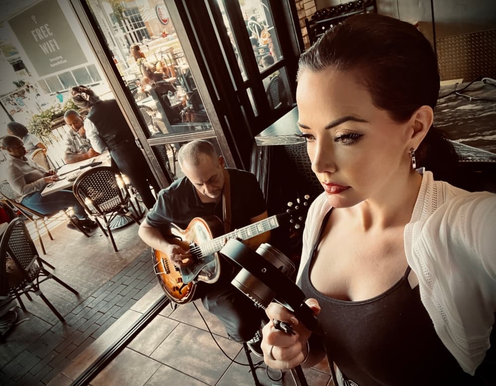 A photo of singer Tianna Hall performing with a guitarist in the background 