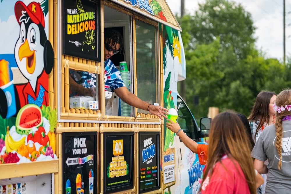 A photo of someone purchasing shaved ice from a Kona Ice food truck 