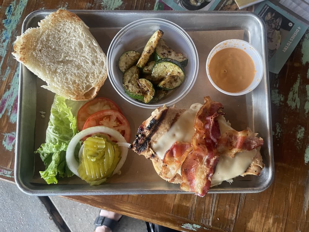 A photo of a Chicken Bacon Swiss Sandwich with a side of zucchini