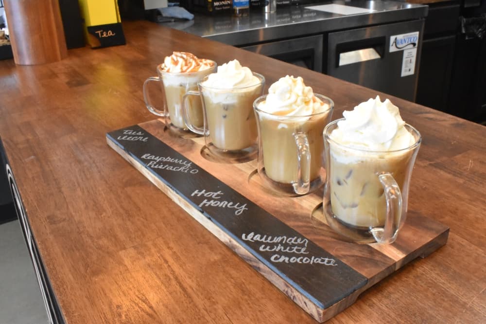 A latte flight ($16), which comes hot or iced, includes tres leches, raspberry pistachio, hot honey and white chocolate lavender lattes. (Lizzy Spangler/Community Impact)