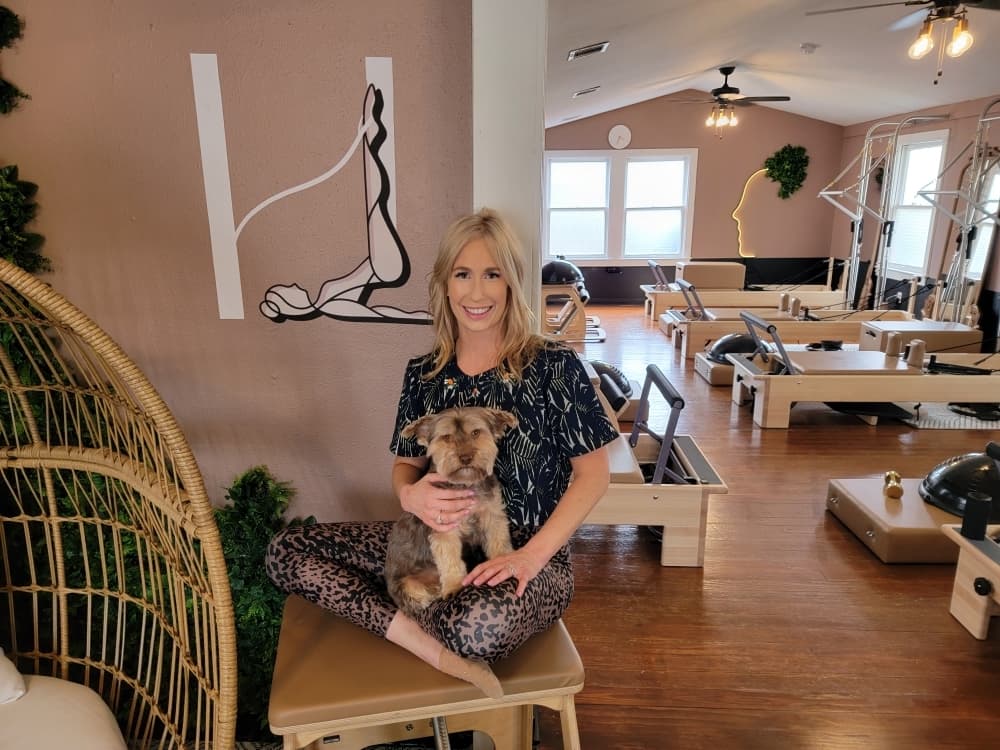 owner posing with her dog inside pilates studio