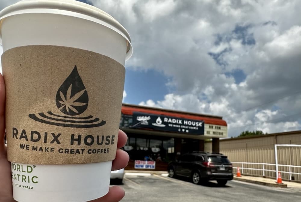 the outside of the location in the background with a coffee in the foreground