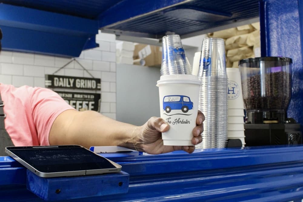 A Herb's House employee hands a hot latte to a Walmart customer. 
