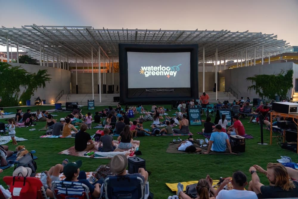 people sitting on grass staring at movie screen