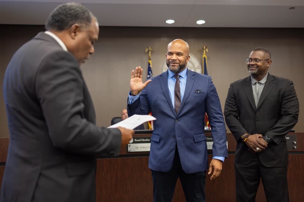 State Rep. Charles Cunningham administers the oath of office to Position 6 Trustee Marques A. Holmes during the June 13 board meeting.