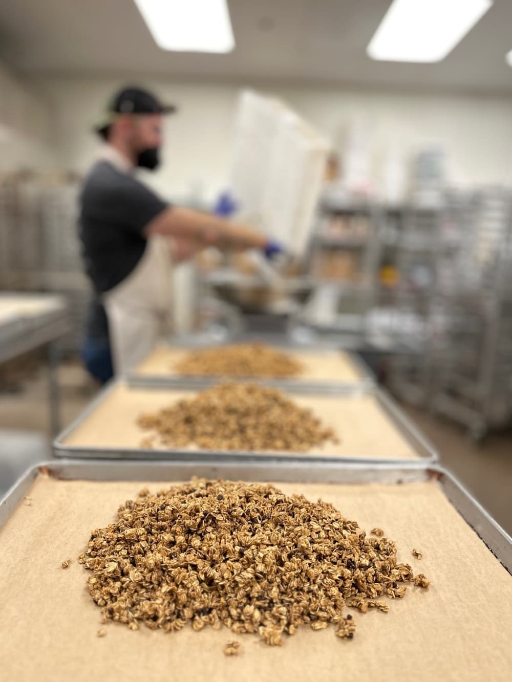 A tray of granola with a worker out of focus in the background