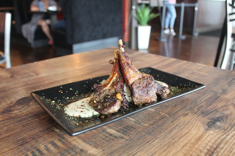 Lamb Chops & Grits ($32.95) is three seasoned and grilled lamb chops served over creamy grits and smothered in Cajun seafood sauce. (Renee Farmer/Community Impact)