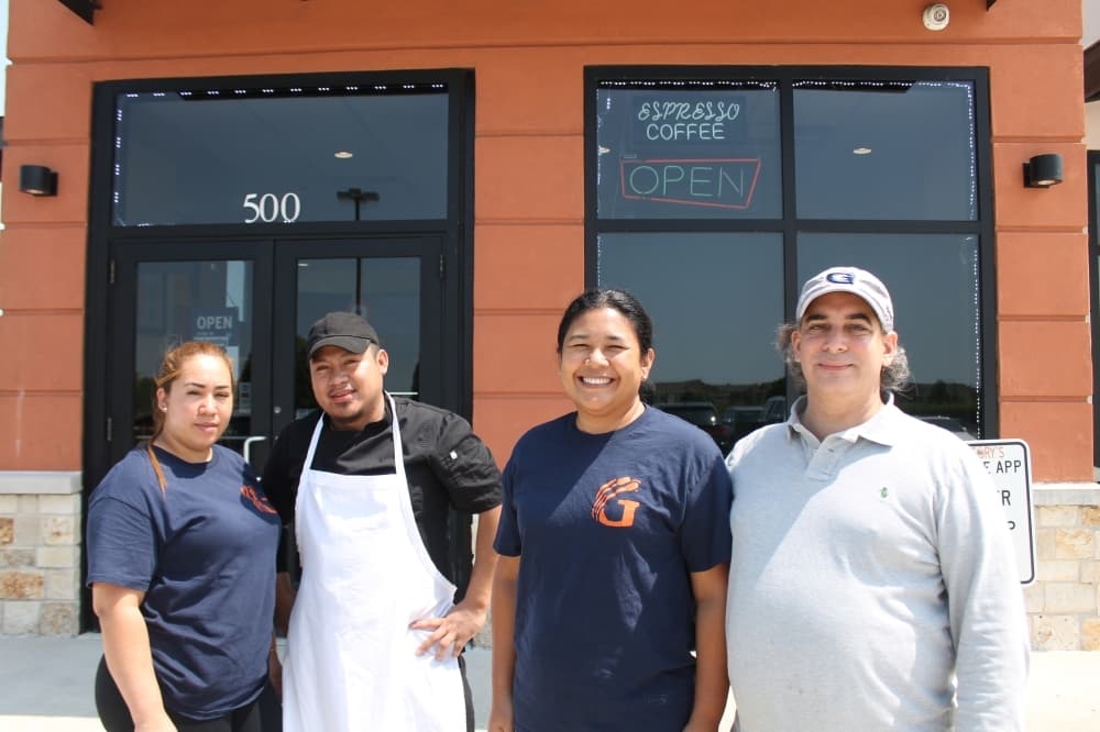 Gregory (right) and Lizbeth Kavadias (second from right) opened the restaurant in 2018. Here they pose with two staff members. (Renee Farmer/Community Impact)