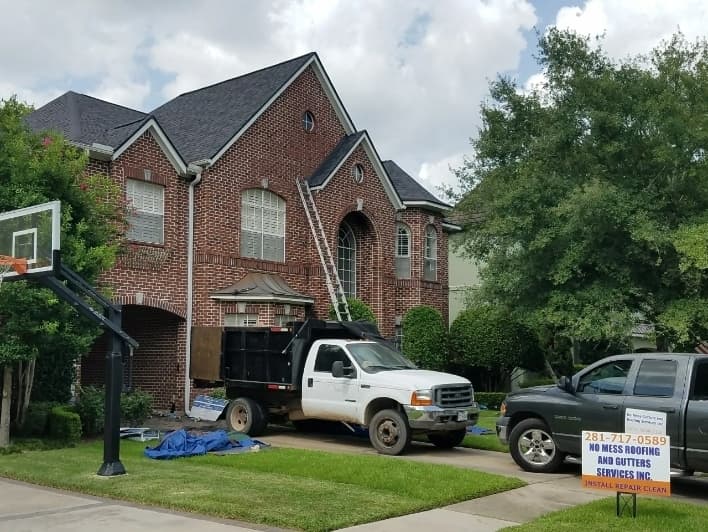 A photo of a house with a new roof and a No Mess Roofing & Gutters sign in the front yard 