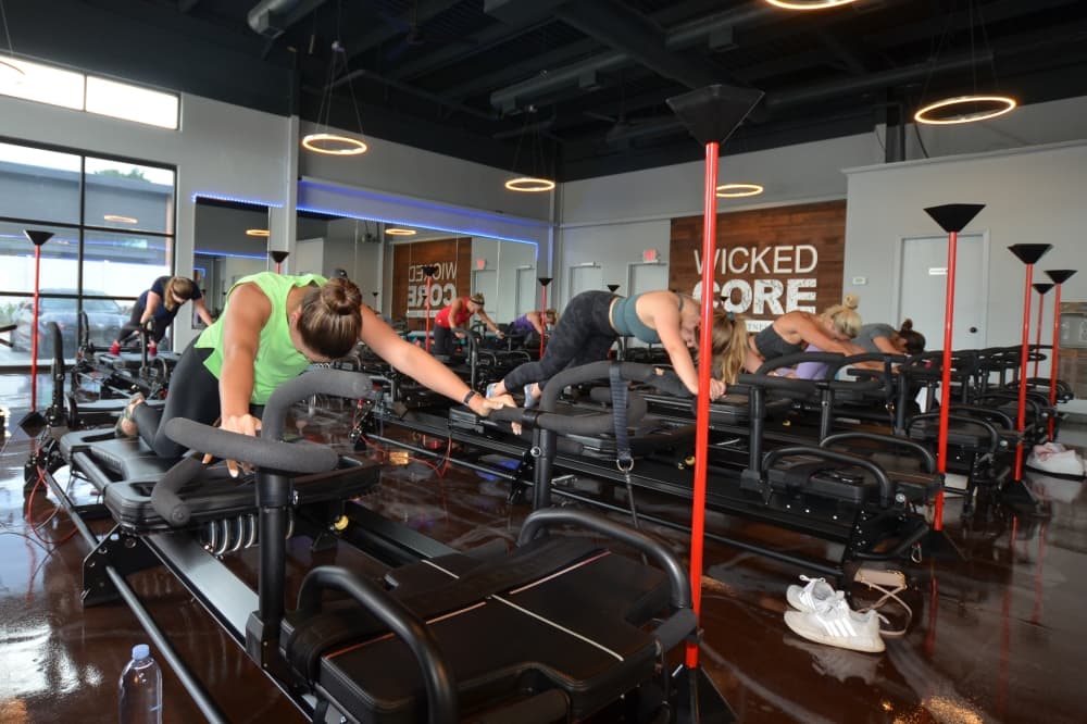 People exercise on Megaformer machines in a lagree fitness studio 