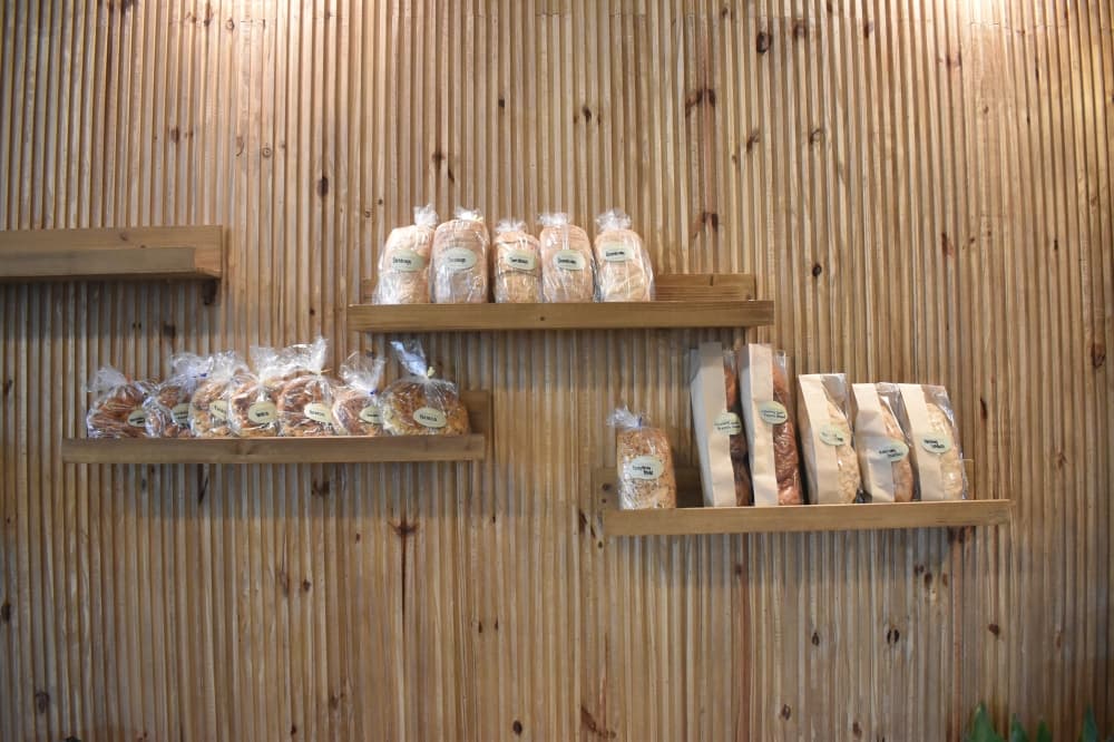 Bagged bread sits on three different shelves on the wall. 