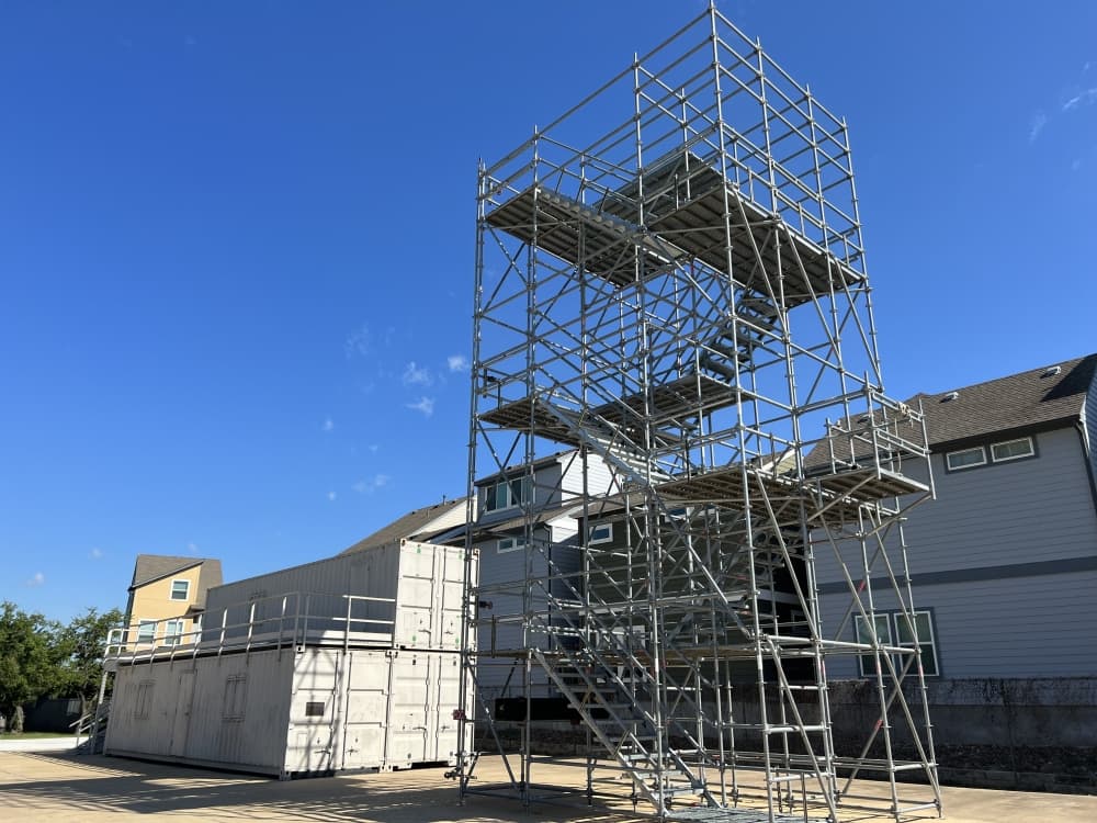 metal training tower with freight containers and apartments in background 