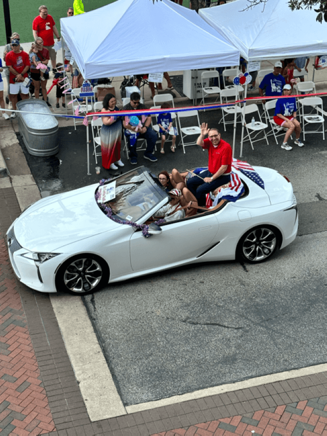 Curtis Null waves from a white car in the parade.