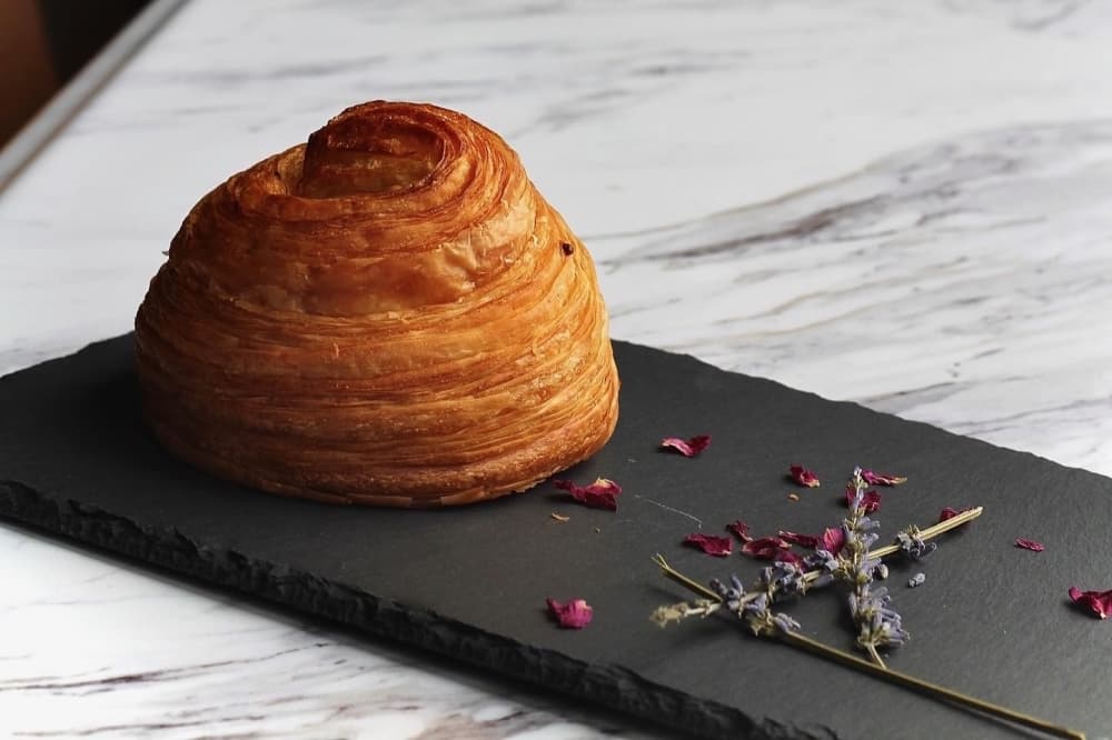 A croissant on a plate with flowers as garnish