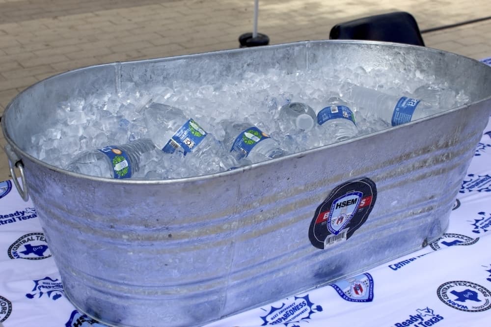 A bucket filled with ice and plastic water bottles on a table.