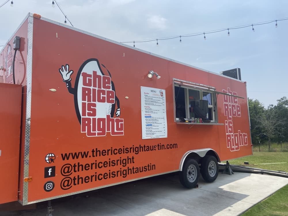 an orange food truck with "the rice is right" sign 