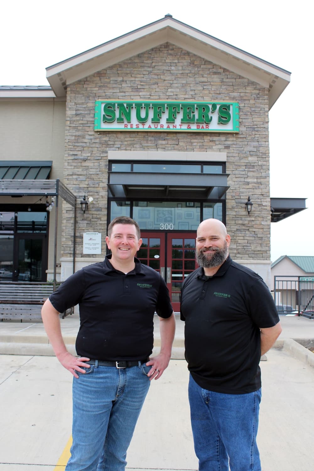 two men stand in front of a restaurant