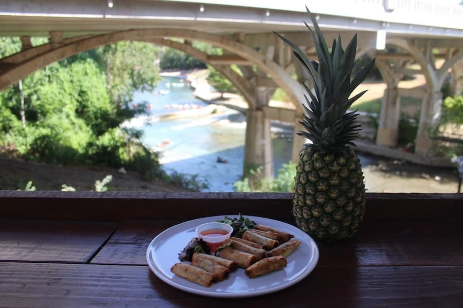 Lumpia on a plate with a pineapple next to it 