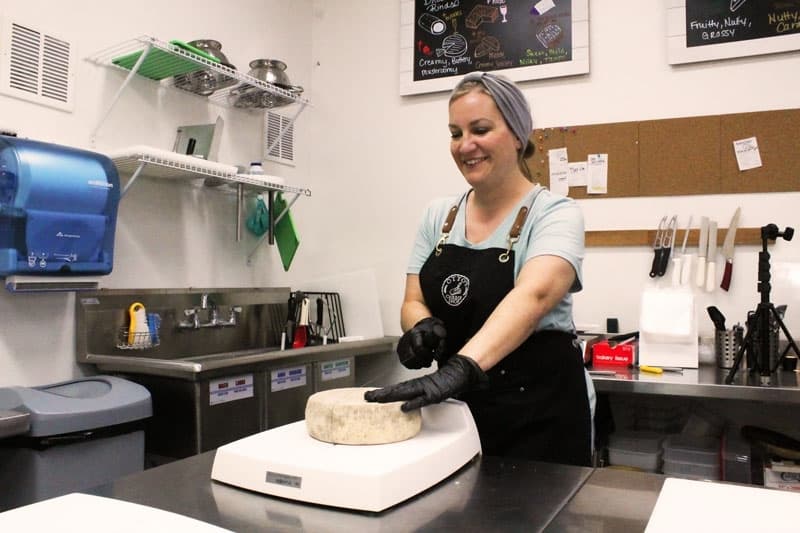 Rachel Pineda cutting cheese in the shop. 