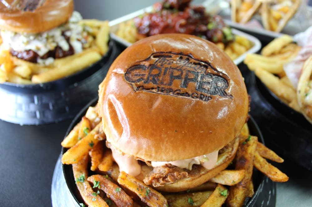 sandwich on a bed of fries with the word gripper burned into the top bun