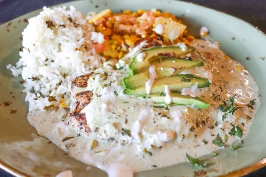 The pollo palomino ($19) comes with grilled chicken breast, Monterey Jack cheese, avocado, and sides of cilantro lime rice and a veggie of the day. (Zara Flores/Community Impact)