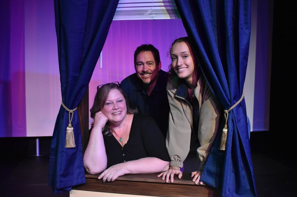 Owner of Black Cat Theater and Academy pose in an artificial window with her family 