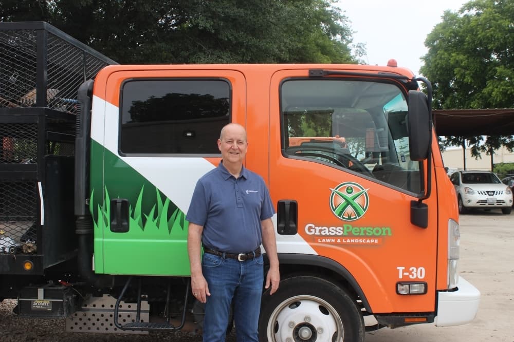 The owner of the business stands next to a work a truck