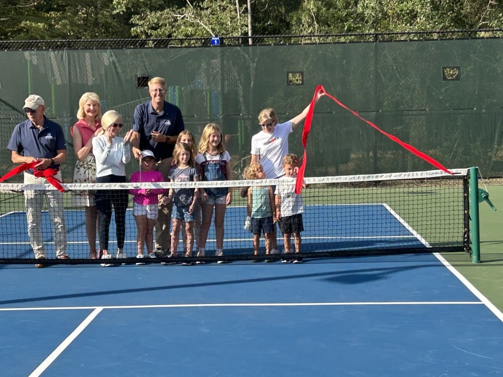 A group of people gather on a pickleball court