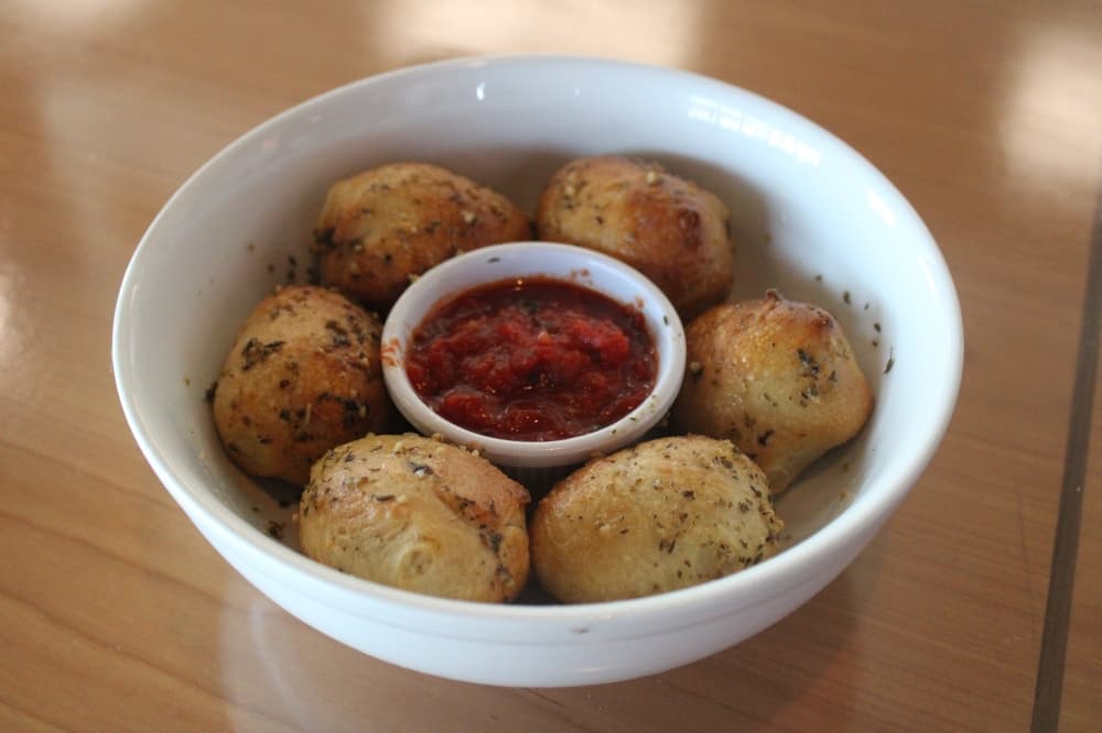 Garlic knots and sauce in a serving dish.