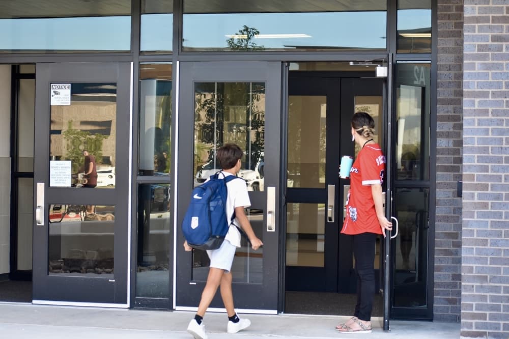 student with large backpack walks into school