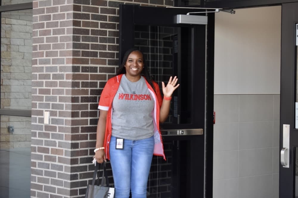 a woman waves at a front door