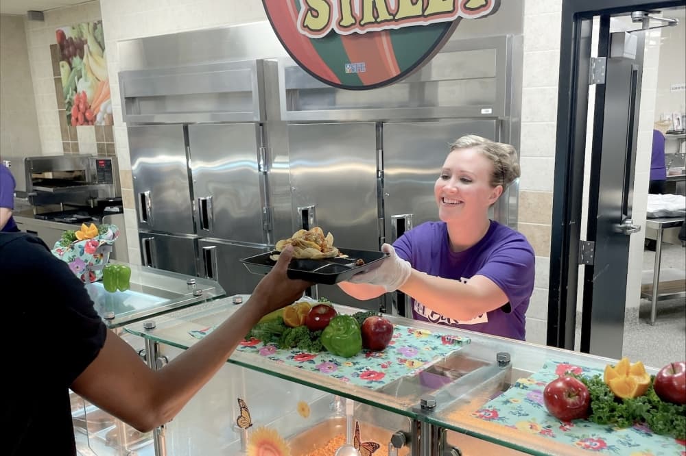 Kelsie Orgil, a member of Liberty Hill ISD’s child nutrition services staff, serves lunch 