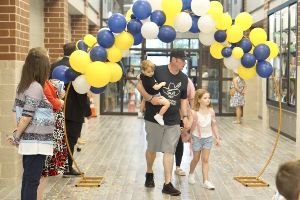 Parents and students walk under a balloon arch celebrating the opening of the new school for the first day. (Cassandra Jenkins/Community Impact)