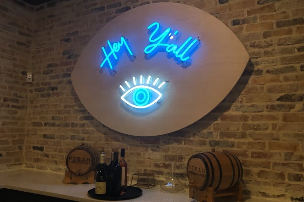 "Hey y'all" neon sign on brick wall