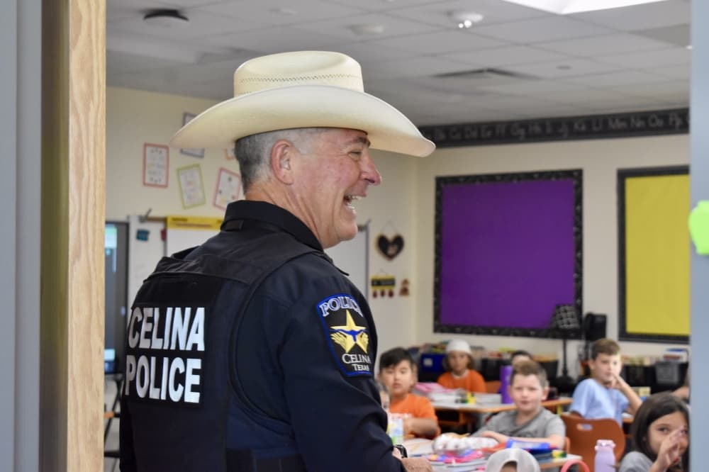 a police officer in a cowboy hat greets a classroom